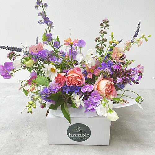 Purple and peach floral arrangement with roses, and garden flowers.
