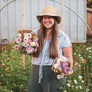 Laura holding a large and medium bouquet of pink summer flowers grown in her city lot garden.