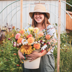 Laura holding a bucket of summer flowers that she harvested from her garden for her subscribers.